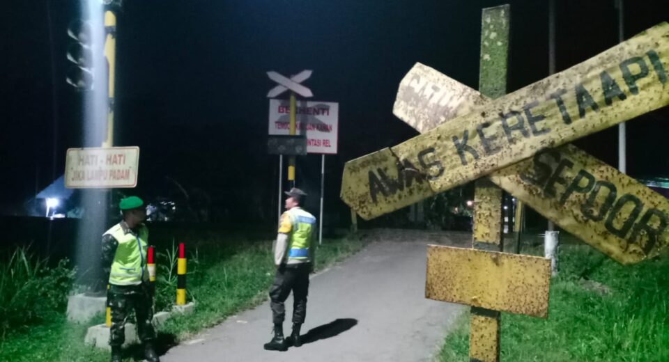 Berikan Rasa Aman, Anggota Koramil Sanankulon Jaga Perlintasan Kereta Api Tanpa Palang