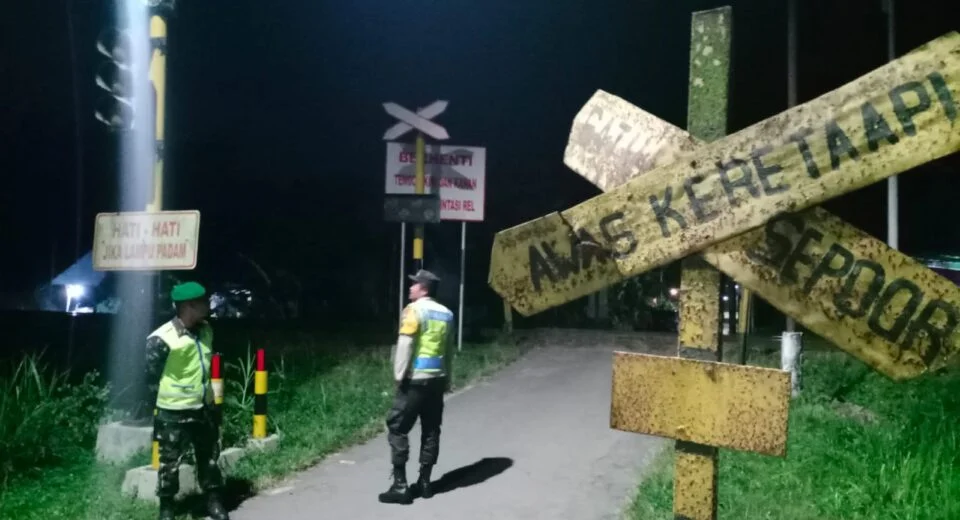 Berikan Rasa Aman, Anggota Koramil Sanankulon Jaga Perlintasan Kereta Api Tanpa Palang
